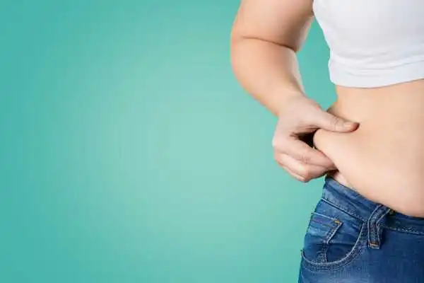 Image of woman pinching her love handles to show weight gain East Kilbride
