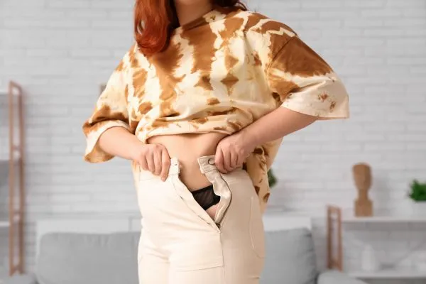 Image of woman trying to do her trousers up after pregnancy weight gain East Kilbride